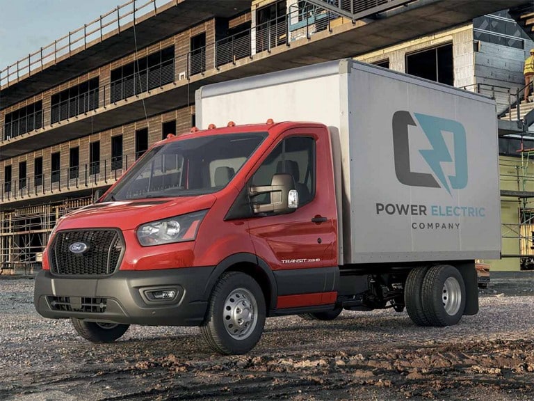 A 2025 Ford Transit® Chassis Cab with box body parked in front of a construction site