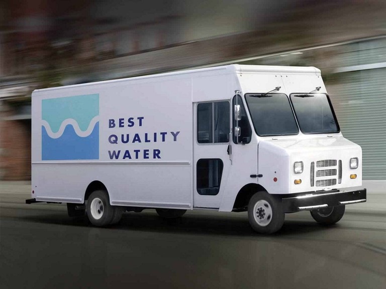 A box body on a 2027 Ford E-Series Stripped Chassis, driving down an industrial street