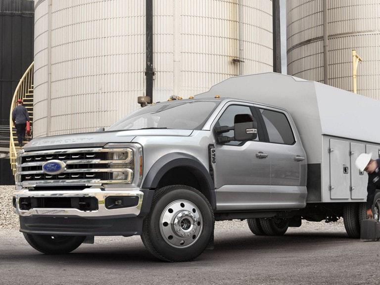 2026 Ford Super Duty® F-450 Lariat® Chassis Cab with utility box parked in front of silos