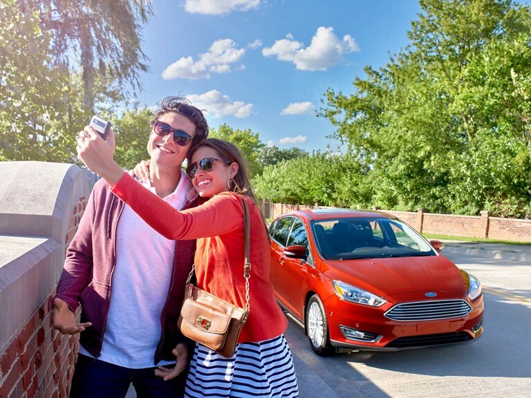 A couple posing for a selfie in front of a 2018 Ford Focus®