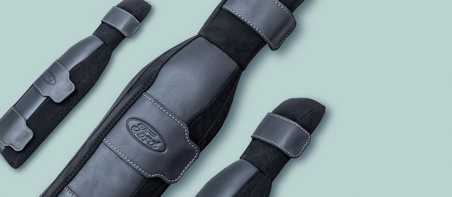 Closeup of three Ford SupportBelt seat belt accessories at different angles on a plain background.