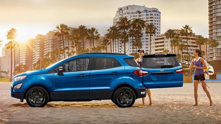 Two women loading beach gear into a 2022 Ford EcoSport® at the beach with the rear swing gate open