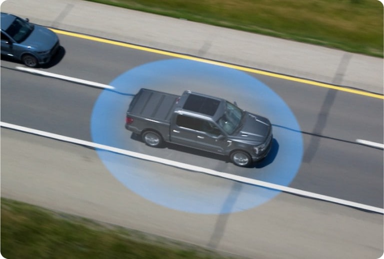 Still image from a video showing an overhead view of a truck with an animated blue circle surrounding it on the road
