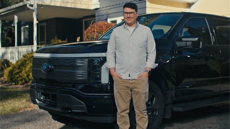 A man stands in front of his head F-150 Lightning® parked in his driveway