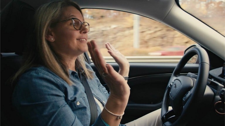 Interior shot of woman in driver seat of 2024 Mustang Mach E®, hands off steering wheel