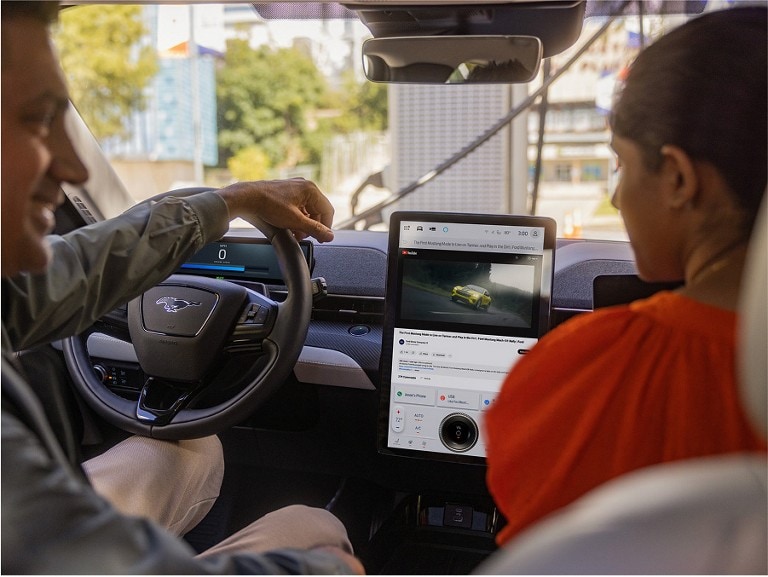 Man and a woman sitting inside a Ford vehicle watching a Ford Mustang Mach-E® Rally YouTube video.