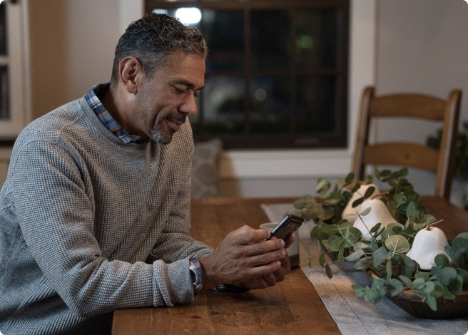 Man using phone at dining room table.