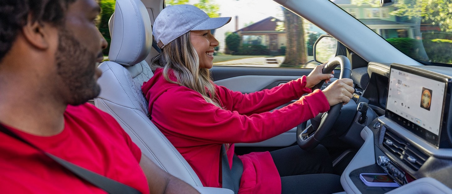 Two women drive a Ford vehicle down a city highway at night.
