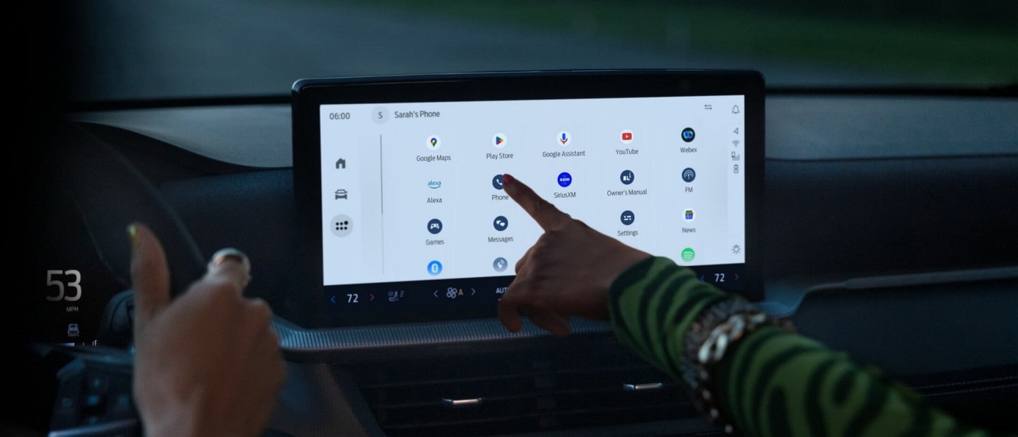 Interior view of a 2025 Ford Explorer® ST SUV with a passenger selecting an available app on the technology touchscreen. 