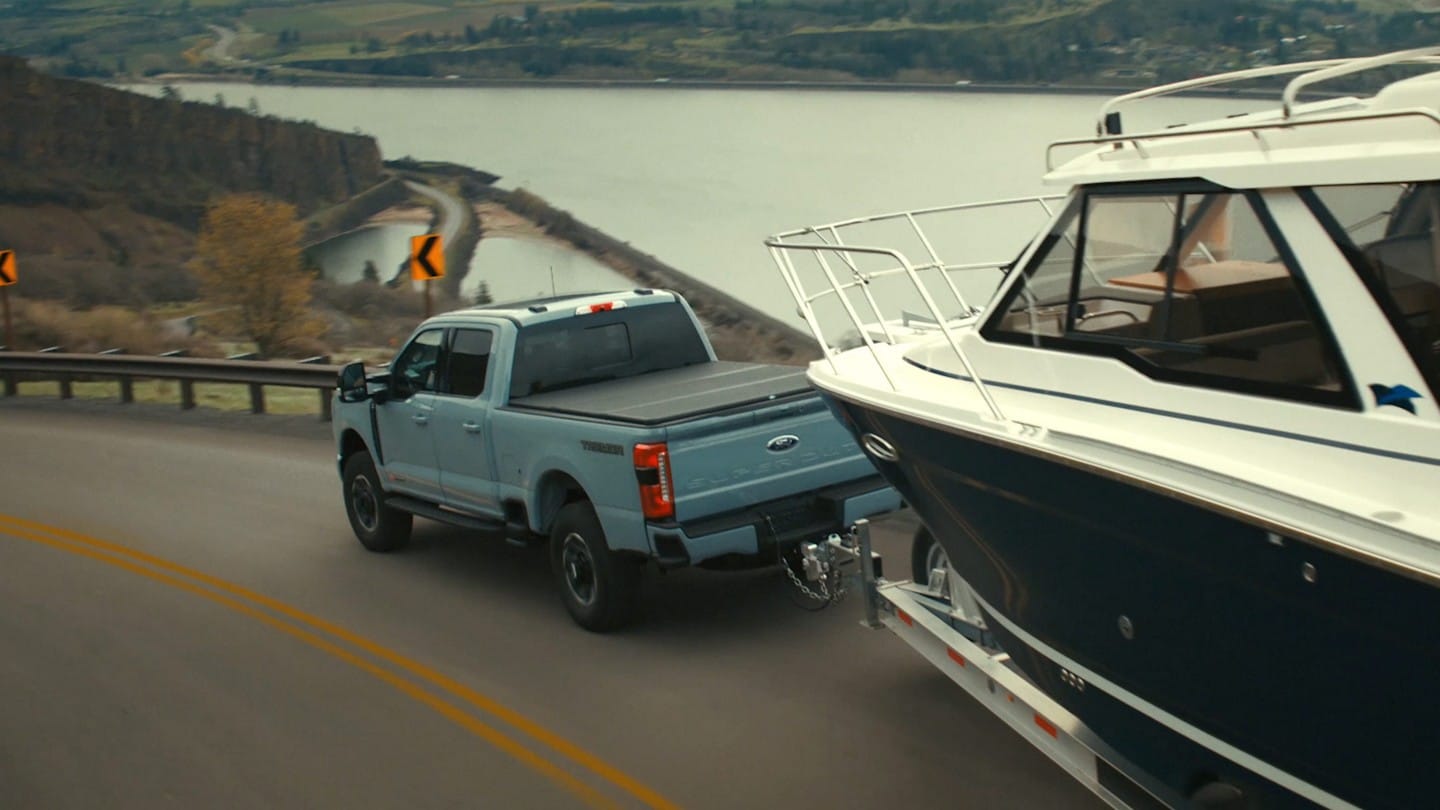 A 2024 Ford F-150® pickup being driven down a road hauling a boat 