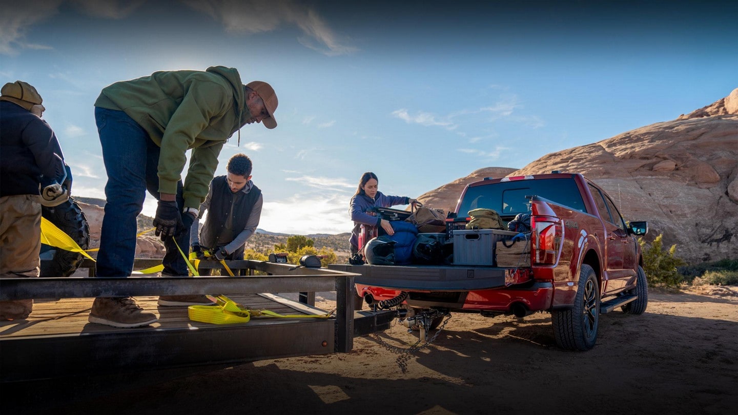 A flatbed trailer being hitched to a Ford F-150® full of gear