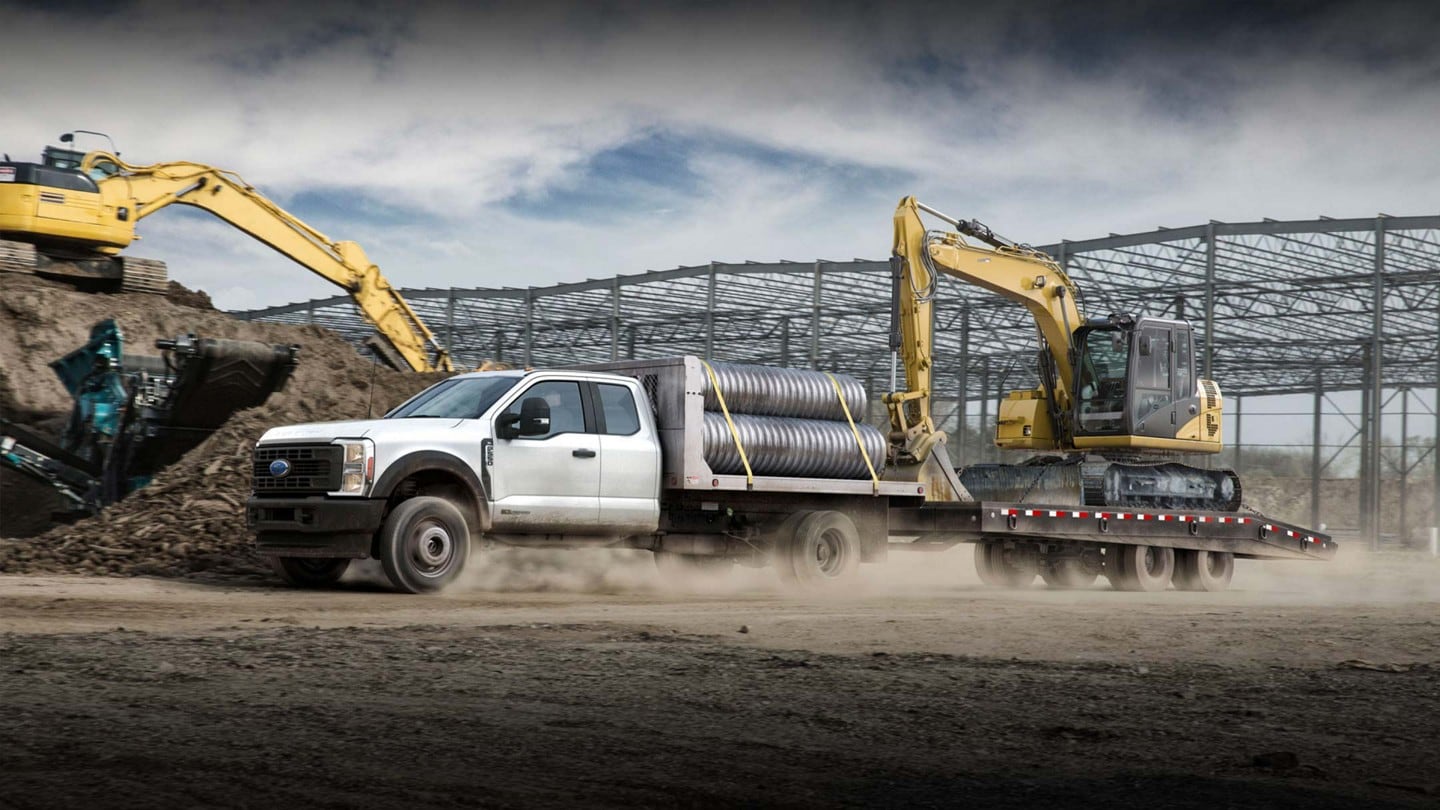 A 2024 Ford F-550® Chassis Cab full of gear towing a big excavator