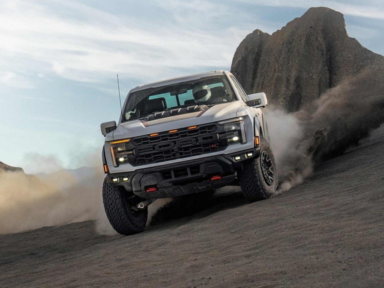A Ford F-150 Raptor R kicking up dust and gravel on a mountain trail