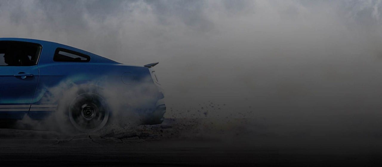 2014 Ford Mustang G T 500 in Velocity Blue with White Stripes with rear wheel making smoke and tearing up road