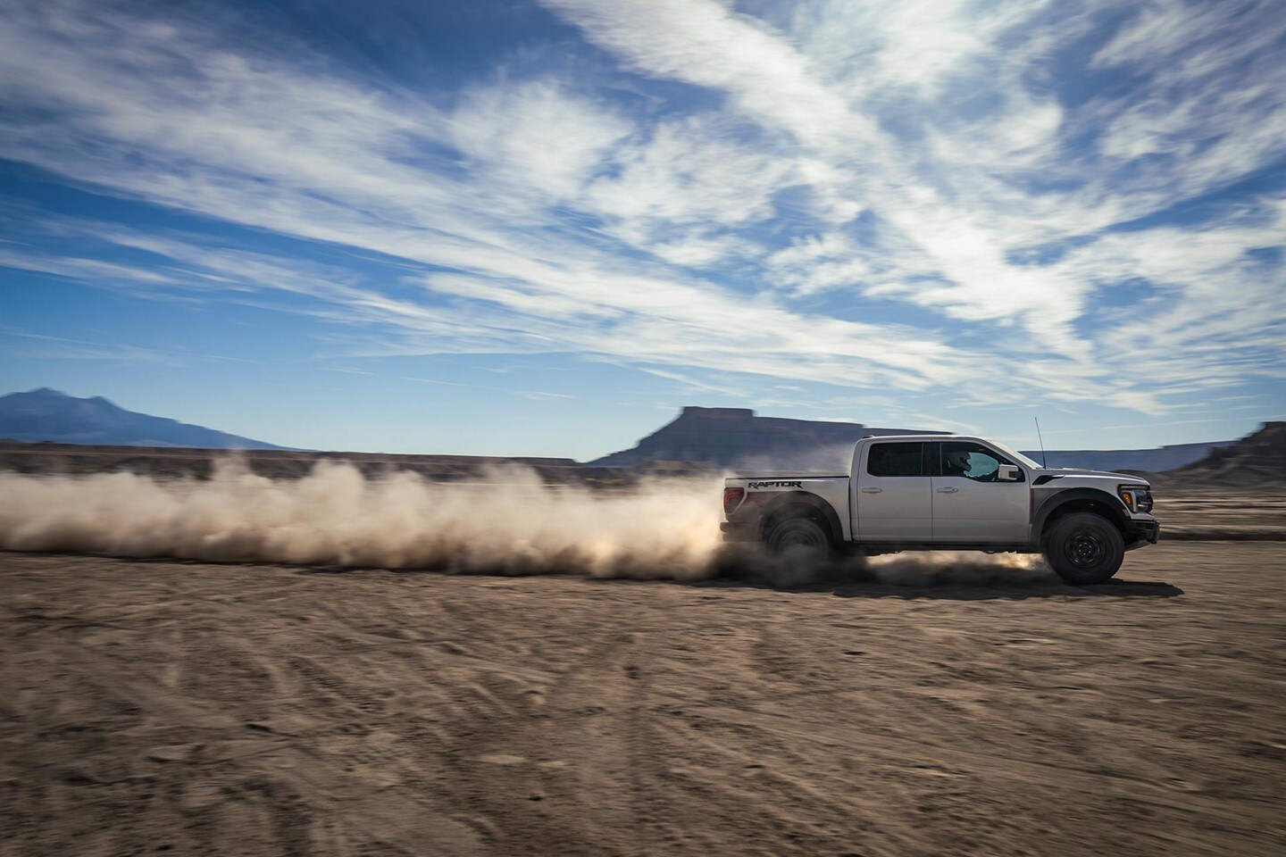 2025 Ford F-150 Raptor pickup truck driving through a desert terrain