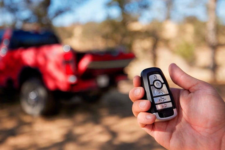 Hand holding key fob with red 2025 Ford Super Duty® pickup in the background