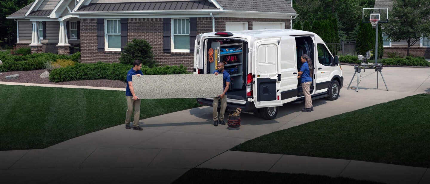 A crew of workers unloading a large slab of granite from a 2025 Ford Transit® van