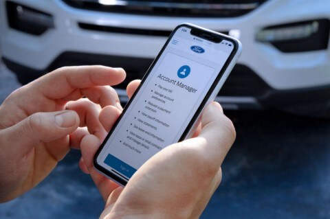 Man holding phone with Ford Credit home page, standing in front of 2020 Explorer X L T