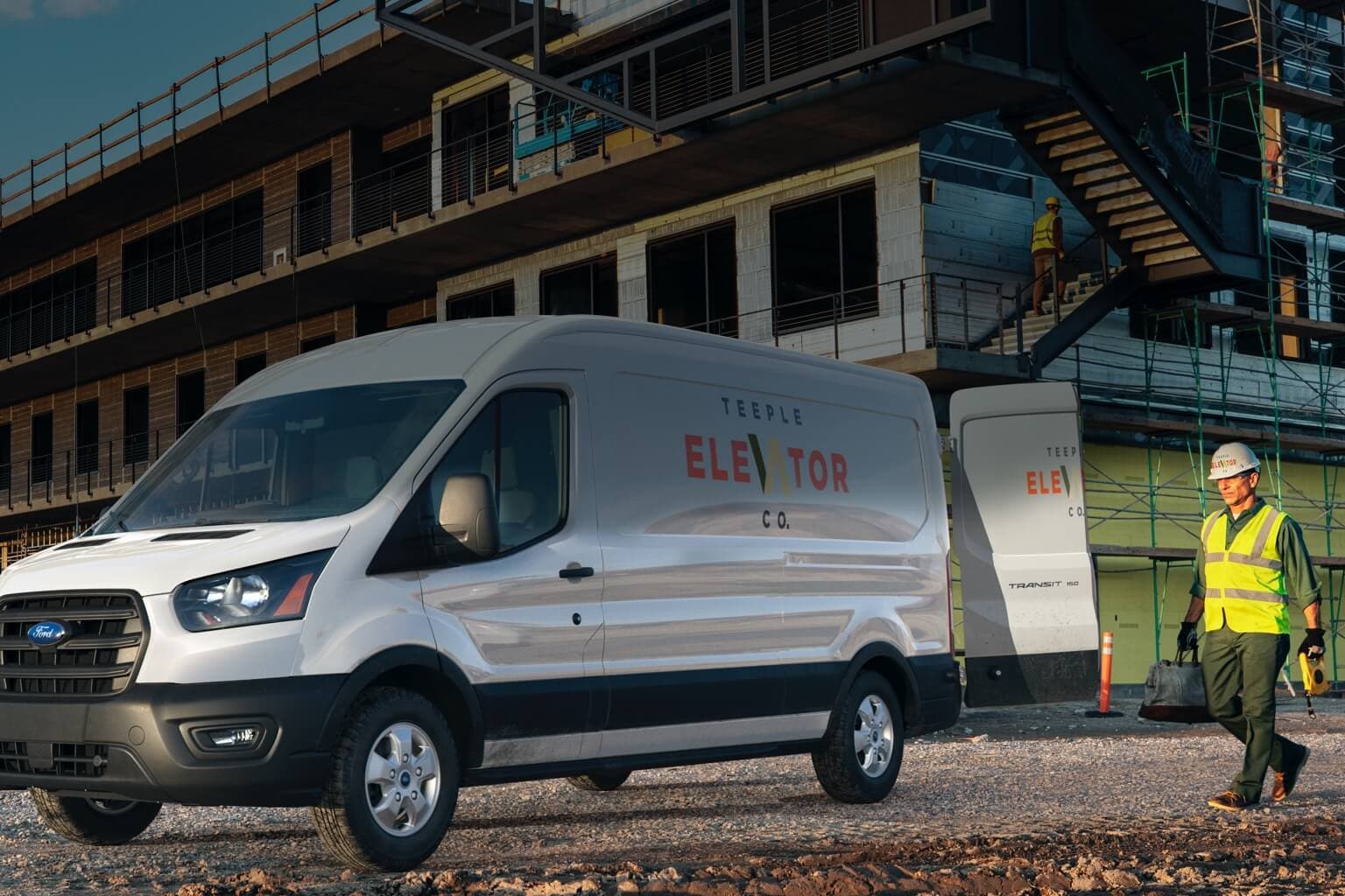 Construction workers near 2020 Ford Transit in White Platinum with open rear doors at work site