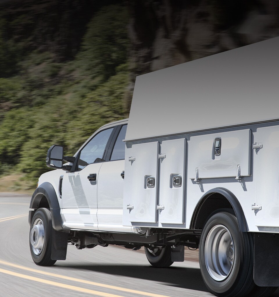  2020 Super Duty Chassis Cab  X L in Oxford White with upfit being driven on curved road near mountains