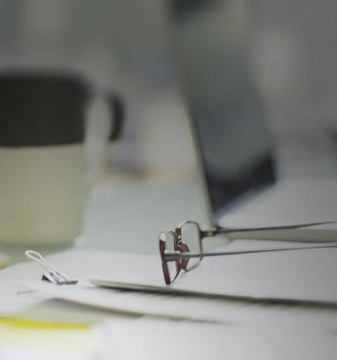 Work desk with assorted items including eyeglasses and laptop