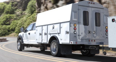 Una Super Duty Chassis Cab X L 2020 en Oxford White con mejora andando por un camino con curvas cerca de las montañas