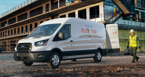 Trabajadores de la construcción cerca de una Ford Transit 2020 en White Platinum con las puertas traseras abiertas en un sitio de trabajo