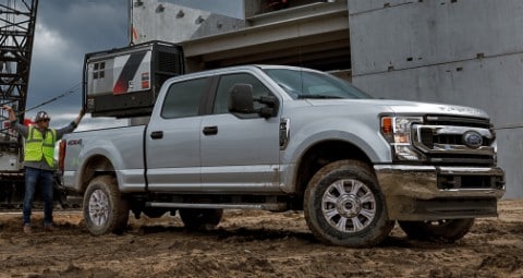 Trabajadores de la construcción cerca de una Ford Transit 2020 en White Platinum con las puertas traseras abiertas en un sitio de trabajo