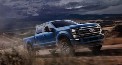 Una Ford Super Duty Crew Cab 2020 en Velocity Blue subiendo una colina en un camino de tierra en el desierto