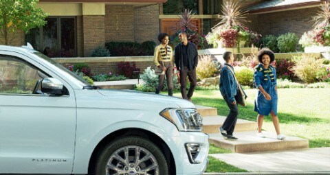 Family of four outside building with white Ford SUV parked out front 