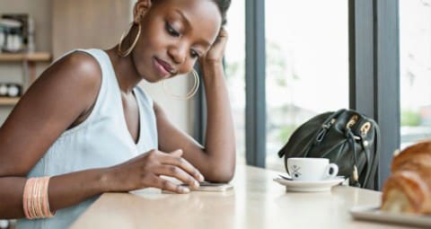 Mujer joven en una mesa usando su teléfono celular