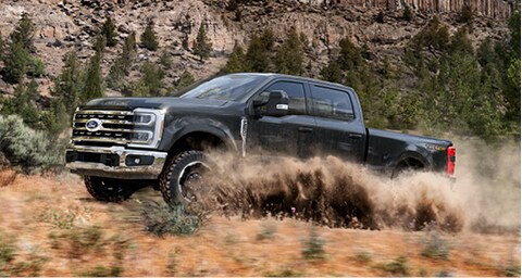 Ford Super Duty® truck is being driven off road through mountainous terrain.
