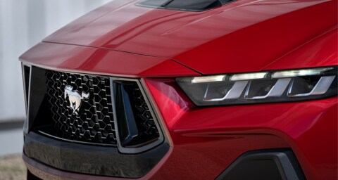 A close-up of the logo on the grille of a red 2024 Ford Mustang® Coupe.