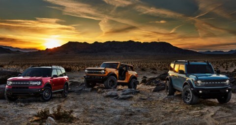 Dos Ford Bronco 2021 y una Ford Bronco Sport 2021 estacionadas en el desierto con una cadena montañosa de fondo