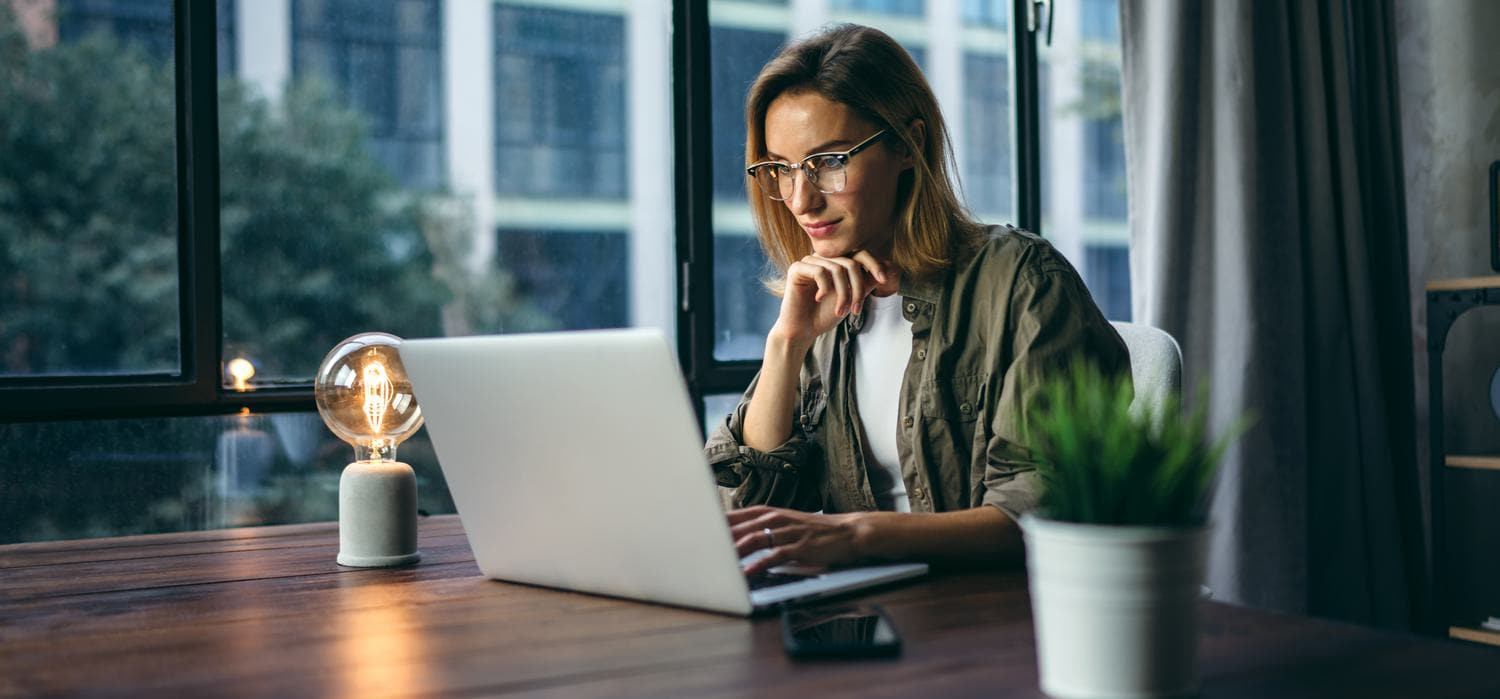 A woman sitting at a table looking at a laptop