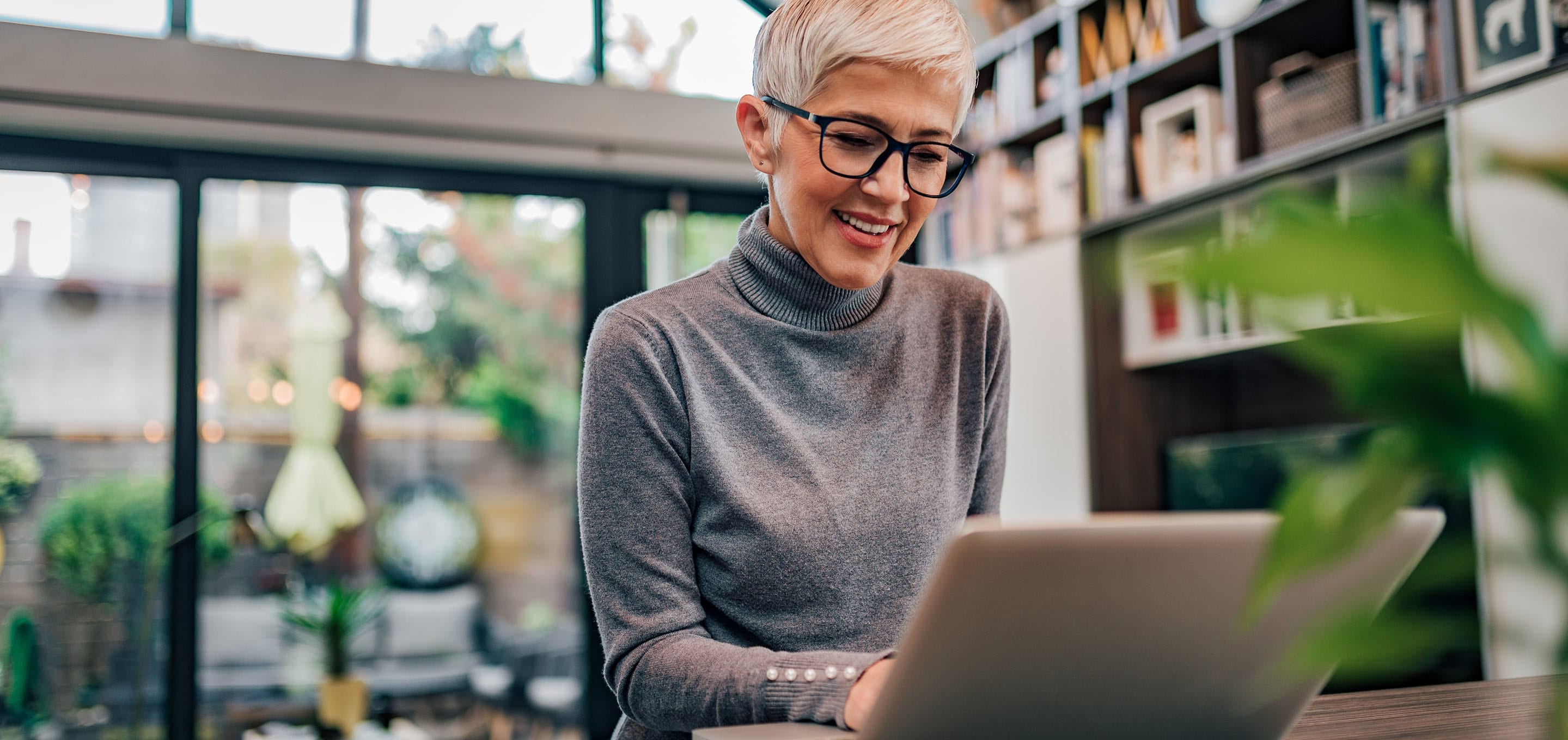 A woman smiling at her laptop screen