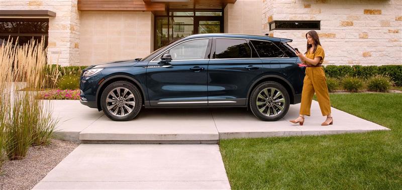 Une femme marchant et regardant son téléphone à côté de son Lincoln Corsair