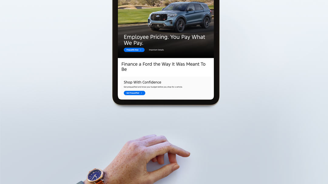 A woman’s hand reaching towards a tablet that shows Ford Credit’s website.