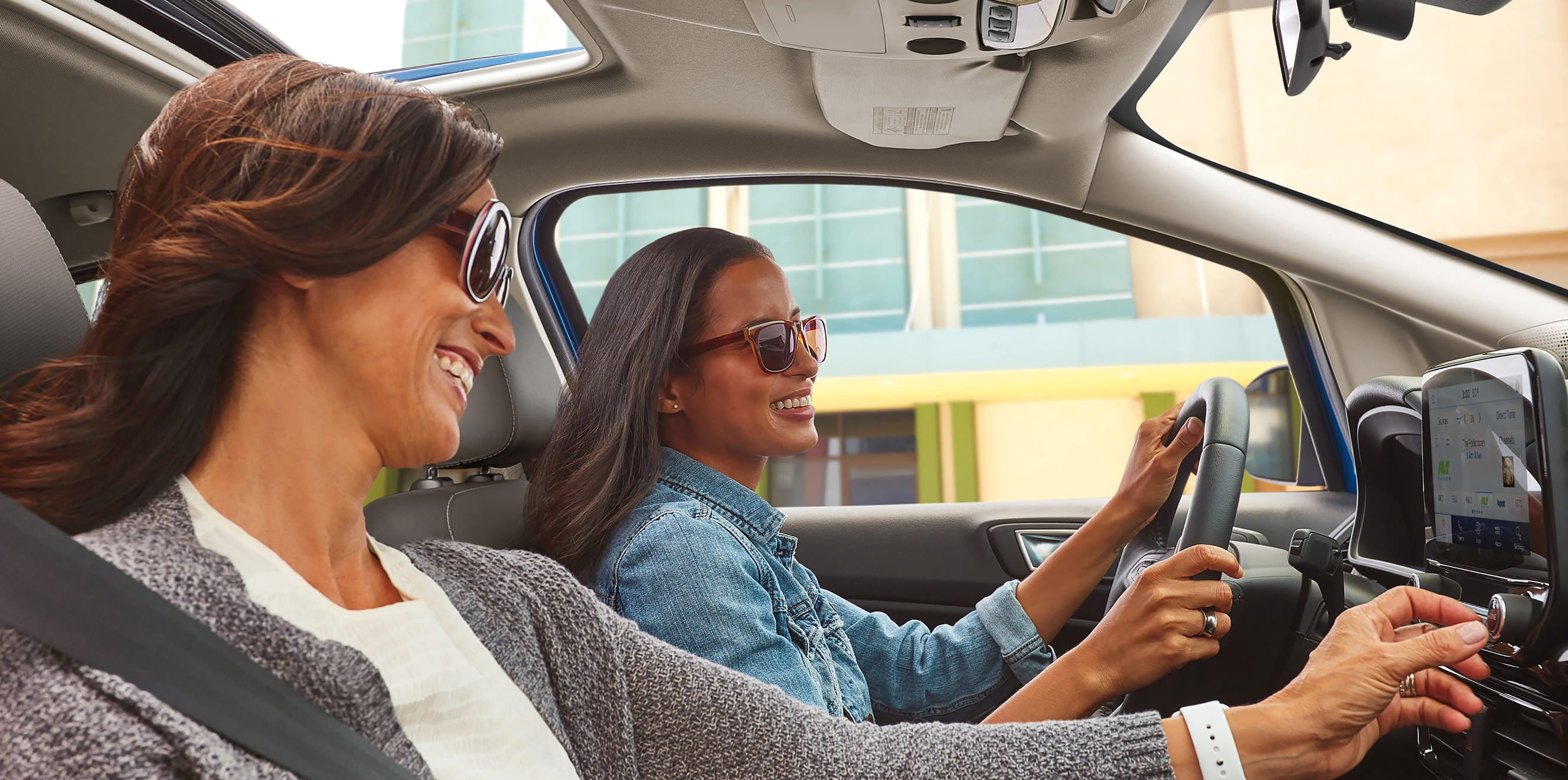 Two women smiling while sitting inside a Ford vehicle.