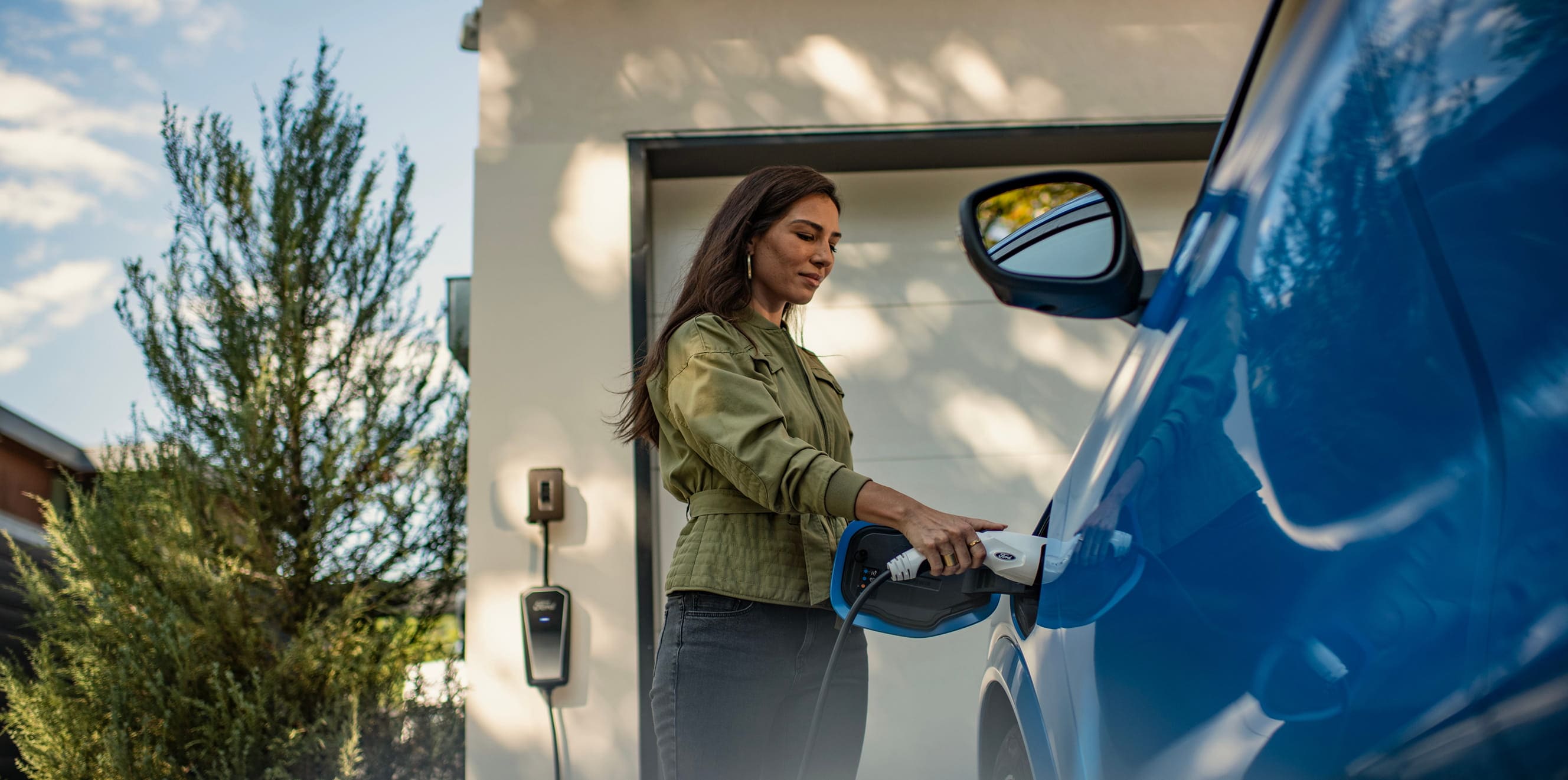 A woman connecting a charger to her Ford EV.