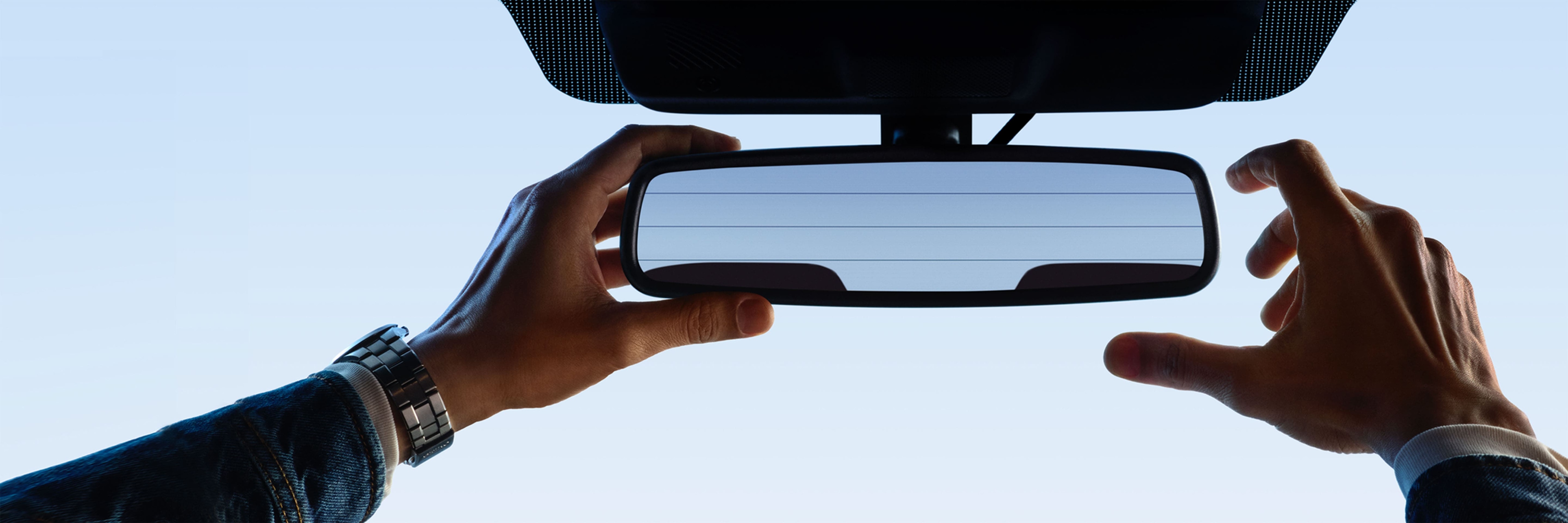 A driver adjusting a rear-view mirror in a Ford vehicle.