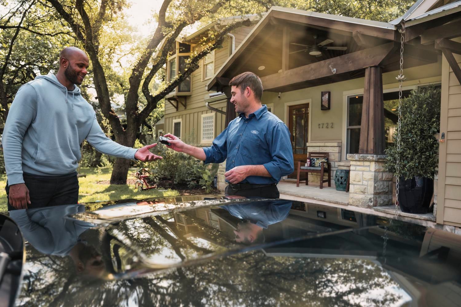 A salesperson handing Ford keys to a smiling customer. 