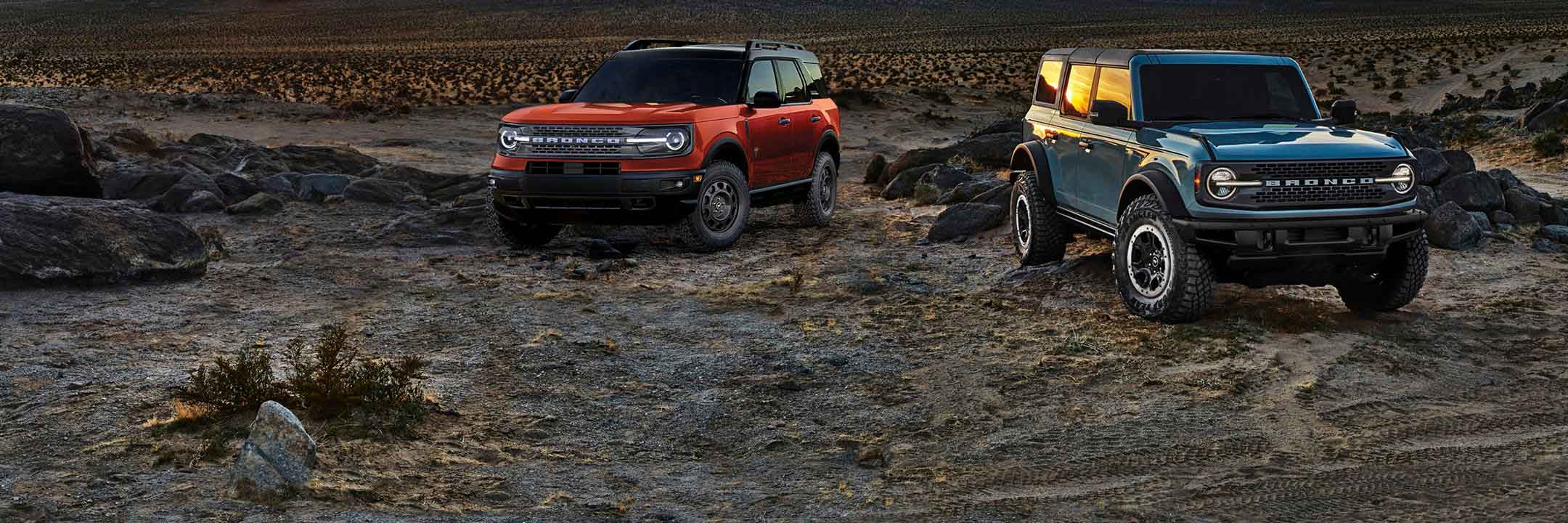 Two Ford Bronco vehicles positioned on a rugged landscape