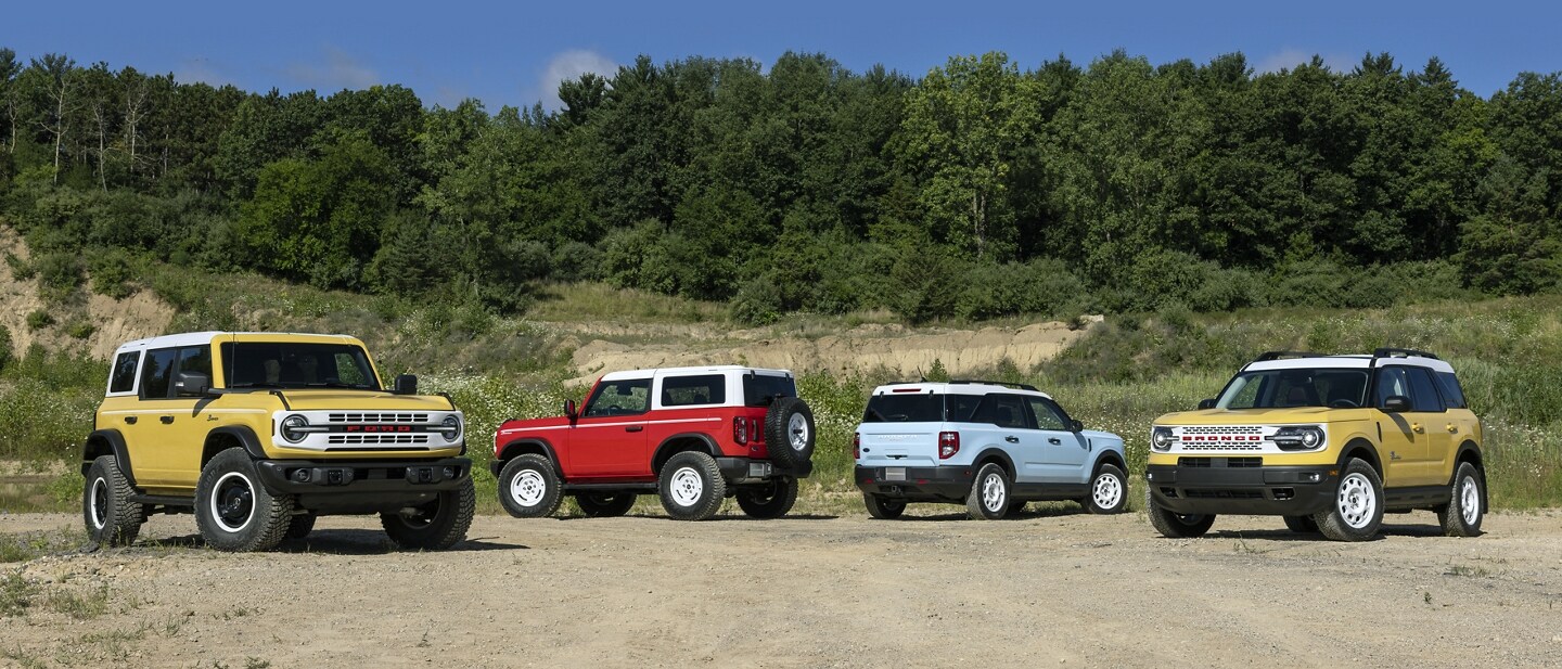 A group of Bronco® and Bronco Sport SUVs parked on a dirt road.