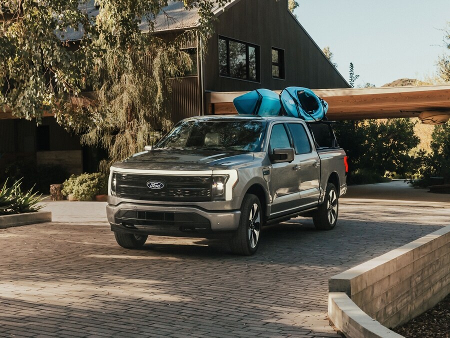 2024 Ford F-150 Lightning with two one person blue canoes strapped to a the truck bed rack