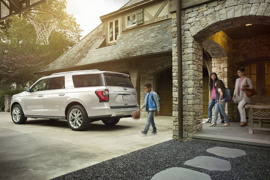 Una familia que se aleja caminando de una Ford Expedition estacionada en la entrada de una casa