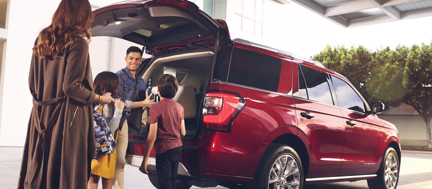 Familia afuera de una SUV Ford estacionada