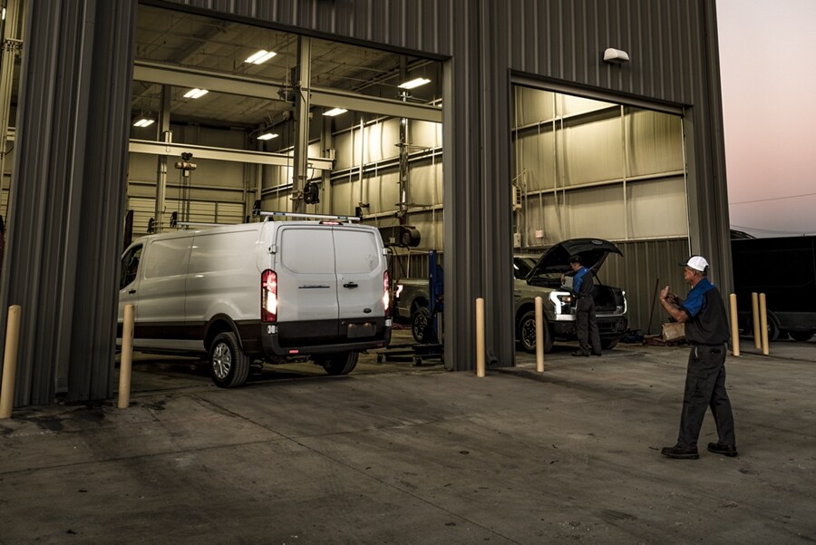 Técnicos de servicio trabajando en una van Ford E-Transit™ 2023 y una camioneta Ford F-150 Lightning® 2023
