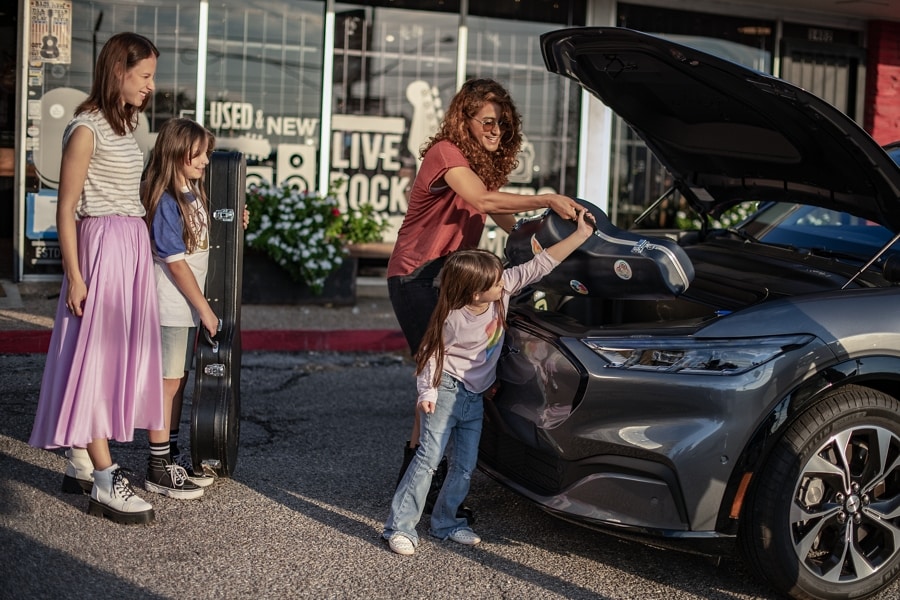 Cuatro personas cargando guitarras en la cajuela delantera de un modelo Ford Mustang Mach-E® 2023