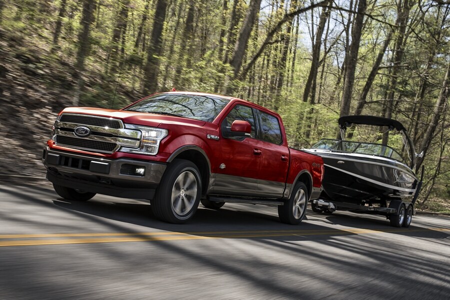 Front three quarter view of a Ford F 1 50 towing a boat on a wilderness highway